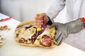 Butcher with short knife deboning prosciutto