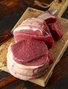 Butcher slicing Fresh Raw top side beef meat on rustic wooden chopping board Royalty Free Stock Photo