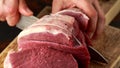 Butcher slicing Fresh Raw top side beef meat on rustic wooden chopping board Royalty Free Stock Photo