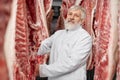 Butcher standing in refrigerator with meat, posing. Royalty Free Stock Photo