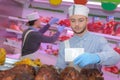 Butcher teaching young one how to sell meat