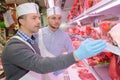 Butcher teaching young one how to sell meat