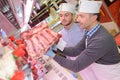 Butcher teaching young one how to sell meat