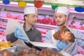 Butcher teaching young one how to sell meat