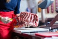 Butcher woman cutting piece of rib meat in her shop