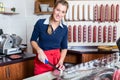 Butcher woman cutting a sausage in the shop