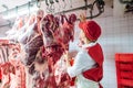 Butcher woman inspecting piece of meat to processed