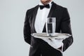 Butler in gloves holding silver tray with glass of water