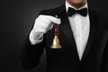 Butler holding hand bell on black background, closeup Royalty Free Stock Photo