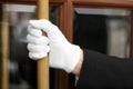 Butler in suit and white gloves opening hotel door, closeup