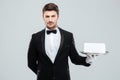 Butler in tuxedo and gloves holding tray with blank card