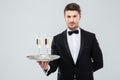 Butler in tuxedo holding tray with two glasses of champagne