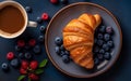 Butter croissant on a plate with berries and a cup of coffee on a dark blue background. Top view of French pasrty on Royalty Free Stock Photo