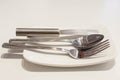 Butter knife, fork and spoon on a white plate Royalty Free Stock Photo