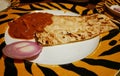 Butter naan (a type of flour based Indian bread) served with kaju masala curry and a slice of onion