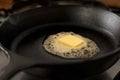 A butter pat melting on a black cast iron frying pan. Royalty Free Stock Photo