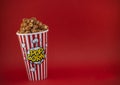 Butter popcorn in a red popcorn cup, snack in the house or cinema on a red background Royalty Free Stock Photo