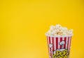 Butter popcorn in a red popcorn cup, snack in the house or cinema on a yellow background Royalty Free Stock Photo