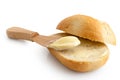 Butter spread on a cut crusty bread roll with a wooden knife iso Royalty Free Stock Photo
