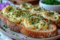 Buttered bread slices topped with creamy swirls and chives on a ceramic plate