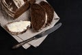 Buttered slice of freshly baked rye bread, table knife on dark background. Artisan sourdough bread. Copy space Royalty Free Stock Photo