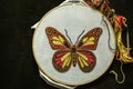 Butterfly embroidered on white cotton fabric stretched on a wooden hoop with scissors and colored threads lie on black plywood Royalty Free Stock Photo