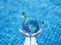 Butterfly drinking water from blue globe on hand. Saving water concept