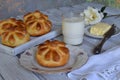 Buttermilk dinner buns in flower form served with butter, knife, glass of milk and jam on wooden background. Fresh baked brioche. Royalty Free Stock Photo