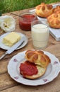 Buttermilk dinner buns in flower form served with butter, knife, glass of milk and jam on wooden background. Fresh baked brioche. Royalty Free Stock Photo