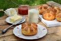 Buttermilk dinner buns in flower form served with butter, knife, glass of milk and jam on wooden background. Fresh baked brioche. Royalty Free Stock Photo