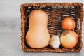 Butternut squash, galic, and onion in a basket, close-up view