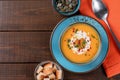 Butternut squash soup with cream, croutons, pumpkin seeds and orange napkin on one brown wooden table. Copy space. Top view