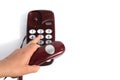 A woman`s hand holds a retro telephone receiver in her hand and presses the buttons to call the subscriber