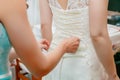 Buttoning bride's wedding dress. Close up.