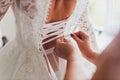 Buttoning the dress on bride. Details of beautiful lace wedding dress. Royalty Free Stock Photo