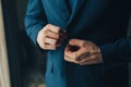 Buttoning a jacket hands close up. Stylish man in suit fastens buttons and straightens his jacket preparing to go out. Preparing