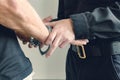 Buttons COP handcuffs an arrested criminal. The man at the police station. Handcuffs on the wrists of the detained man