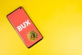 Bux icon on phone with Bitcoin on yellow background