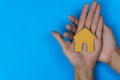 Buy or rent. A small house model made by paper cut on a man hand on  blue background Royalty Free Stock Photo