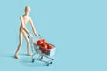 Buyer as wooden dolls with grocery trolley and tomatoes