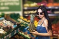 Buyer chooses pineapple in the store. Girl buys healthy fruits