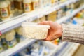 Buyer hand with plastic container of cottage cheese in the grocery store