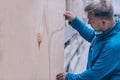 A buyer in a hardware store selects a product. A man holds in his hand a sheet of plywood