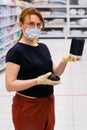 A buyer in a medical mask chooses products in a supermarket. Sale of household goods in the store