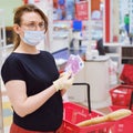 A buyer in a medical mask recounts money euros at the supermarket checkout