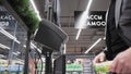 Buyer scans product through barcode scanner at self-service checkout ACO in supermarket. Assisted checkout SCO with