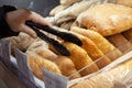 Buying bread at the store. A customer takes fresh bread with tongs at a grocery store.