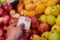 Buying fruits in the supermarket. the buyer gives money for the purchase. 10 euro banknote in hand. Apples, pomegranates Royalty Free Stock Photo