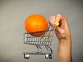 Woman holding shopping cart with orange inside Royalty Free Stock Photo