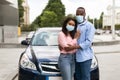 Happy black couple in masks standing near car and hugging Royalty Free Stock Photo